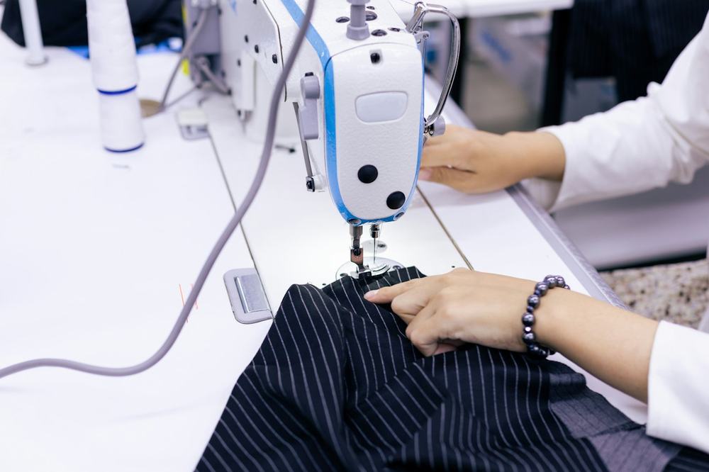 A woman sewing a striped garment on a sewing machine